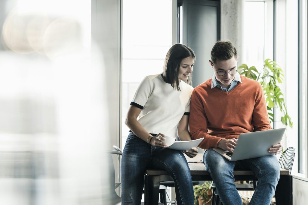 Casual businessman and woman with laptop meeting in office